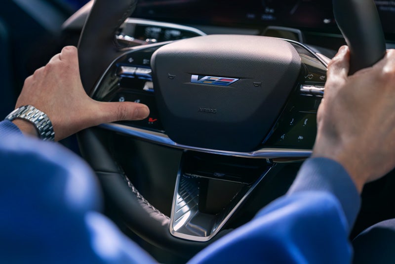 Close-up of a Man About to Press the V-Button on the 2026 OPTIQ-V Steering Wheel | Ed Morse Sawgrass Cadillac in Sunrise FL